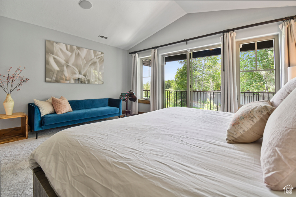 Carpeted bedroom with vaulted ceiling, access to exterior, and multiple windows