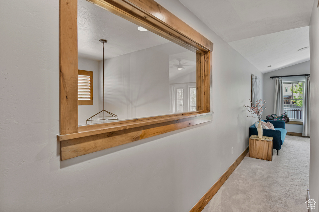 Corridor with carpet floors, lofted ceiling, plenty of natural light, and baseboards