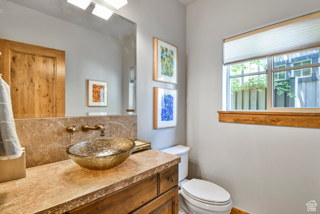 Bathroom featuring decorative backsplash, toilet, and vanity