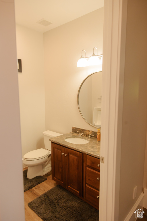 Half bathroom with wood finished floors, vanity, and toilet