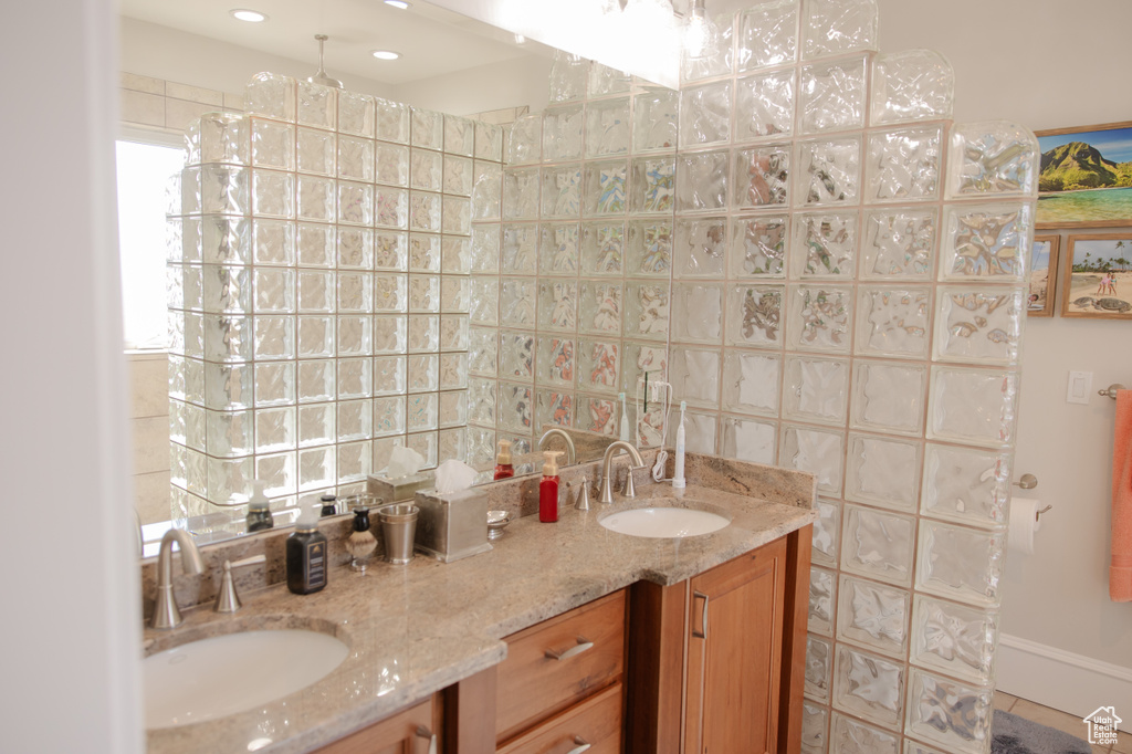 Bathroom featuring double vanity, tasteful backsplash, and tile walls