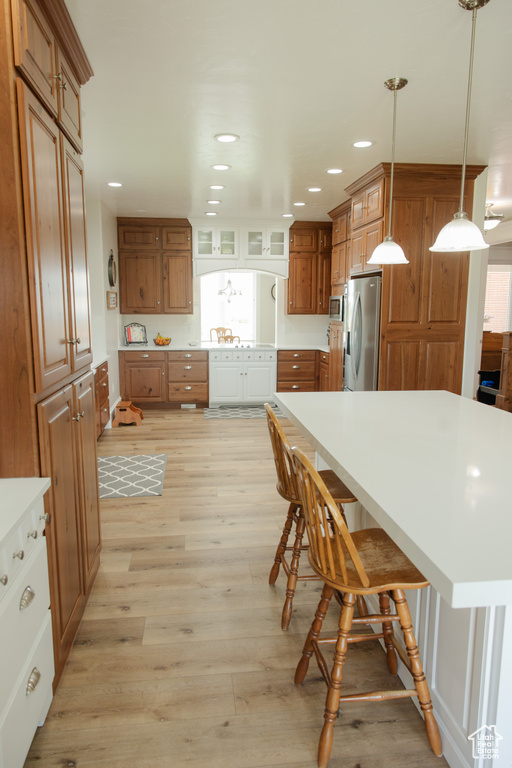Kitchen featuring appliances with stainless steel finishes, brown cabinetry, light wood-style floors, recessed lighting, and light countertops
