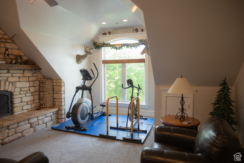 Workout area with plenty of natural light, vaulted ceiling, ceiling fan, a fireplace, and carpet floors