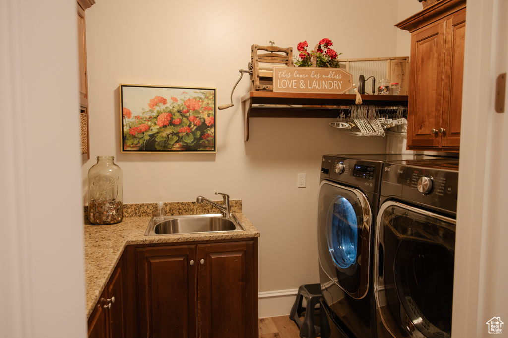 Laundry room featuring washer and clothes dryer, cabinet space, wet bar, and wood finished floors