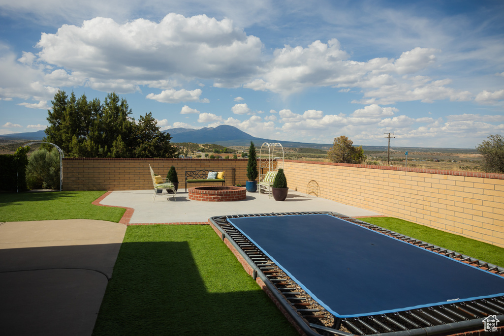 View of yard with an outdoor fire pit, a mountain view, and a patio