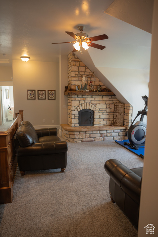 Living room with carpet, ceiling fan, and a stone fireplace
