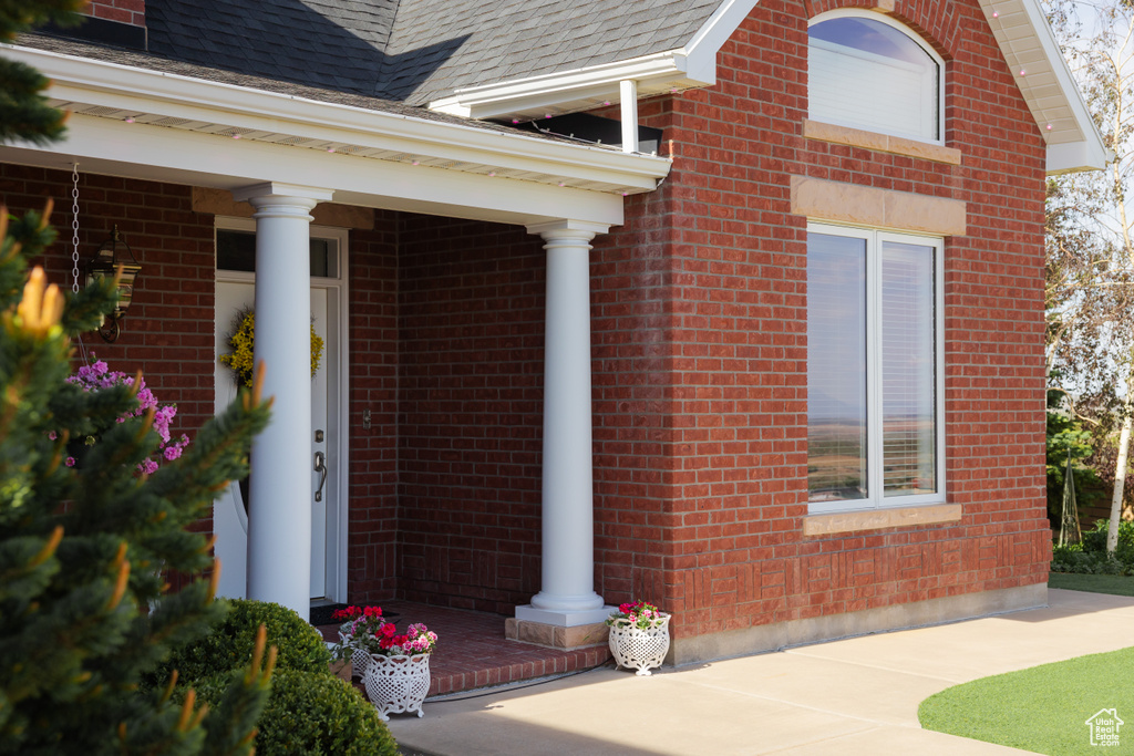 View of exterior entry featuring brick siding and roof with shingles