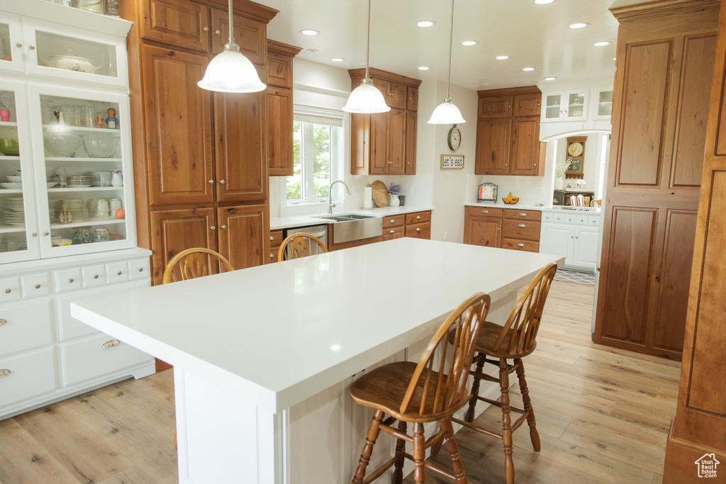 Kitchen with light wood-style floors, a kitchen bar, brown cabinetry, a kitchen island, and recessed lighting