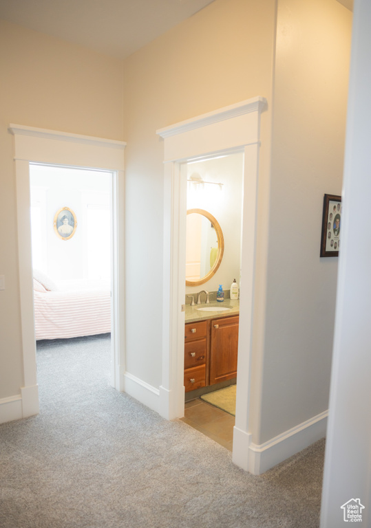 Corridor with light colored carpet, a sink, and baseboards