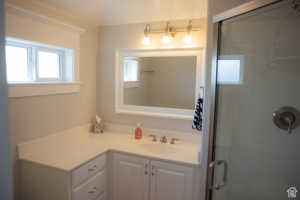 Bathroom featuring healthy amount of natural light, vanity, and a shower stall