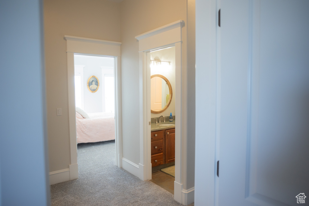 Corridor featuring carpet floors, a sink, and baseboards