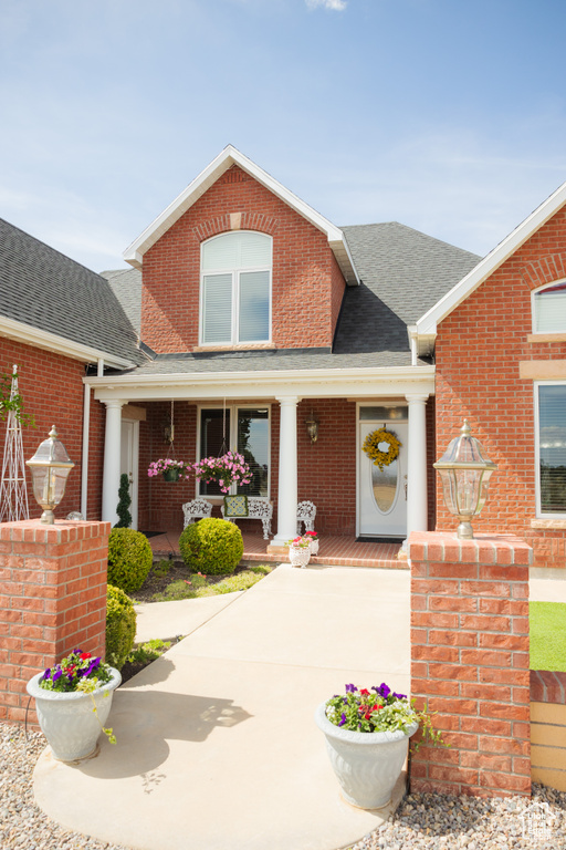 View of front of home featuring a porch, brick siding, and a shingled roof