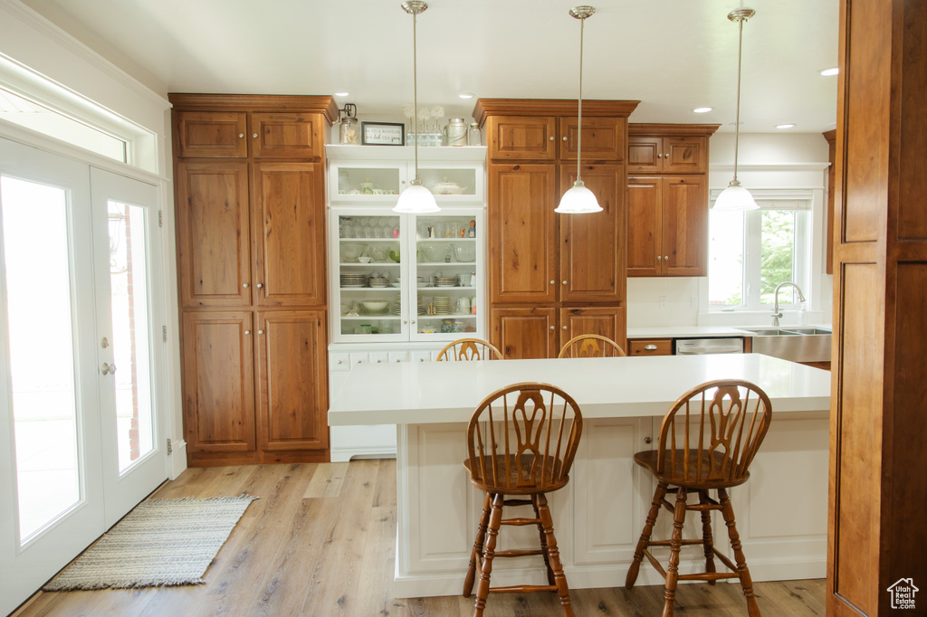 Kitchen featuring a sink, a kitchen bar, light countertops, brown cabinets, and recessed lighting
