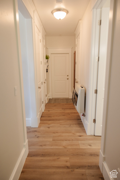 Hall with heating unit, light wood-type flooring, and baseboards