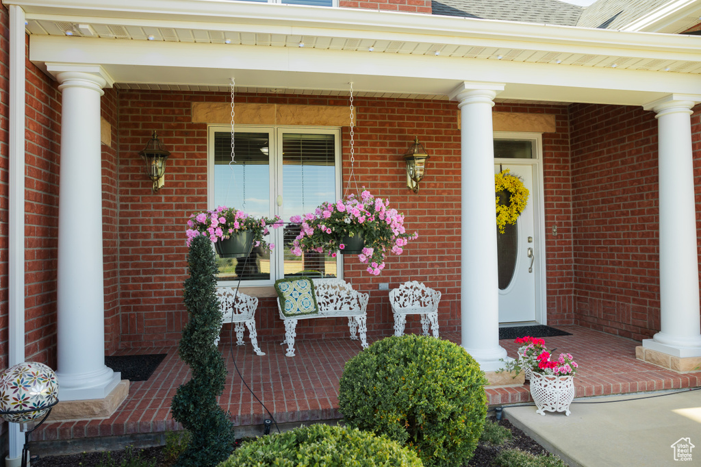 Entrance to property featuring covered porch and brick siding