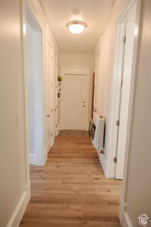 Corridor featuring light wood-style floors, baseboards, and a wall unit AC