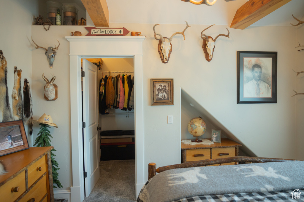 Carpeted bedroom featuring a spacious closet, a closet, and beam ceiling