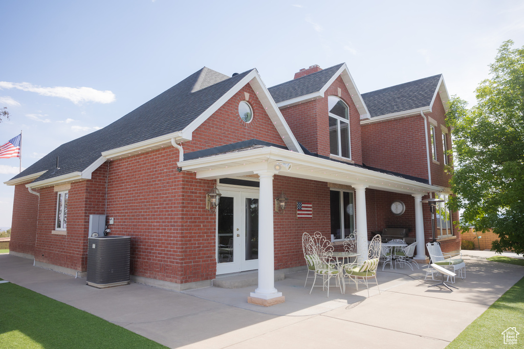 View of front of house featuring french doors, brick siding, central AC unit, and roof with shingles