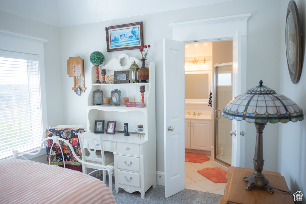 Bedroom featuring light tile patterned flooring, ensuite bath, a sink, and an office area