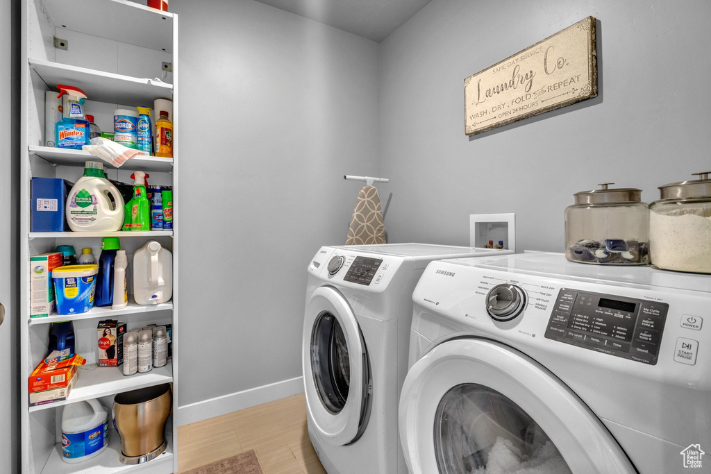 Laundry area featuring washing machine and clothes dryer, baseboards, and wood finished floors