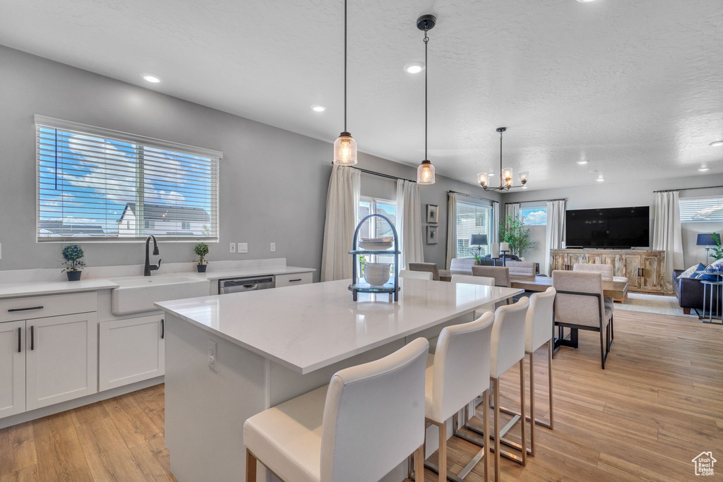 Kitchen featuring a sink, a center island, light countertops, light wood finished floors, and a breakfast bar area