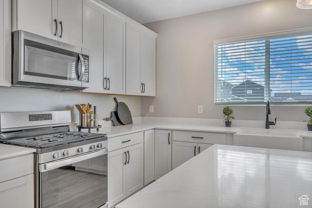 Kitchen featuring appliances with stainless steel finishes, a sink, and white cabinets