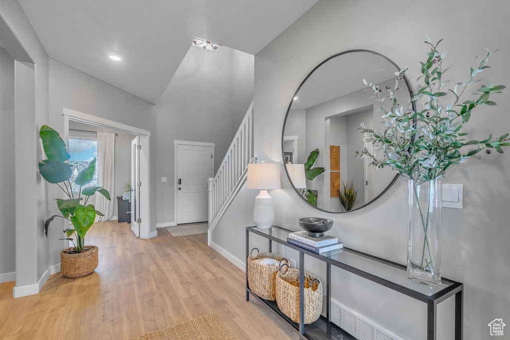 Foyer with baseboards, wood finished floors, and stairway