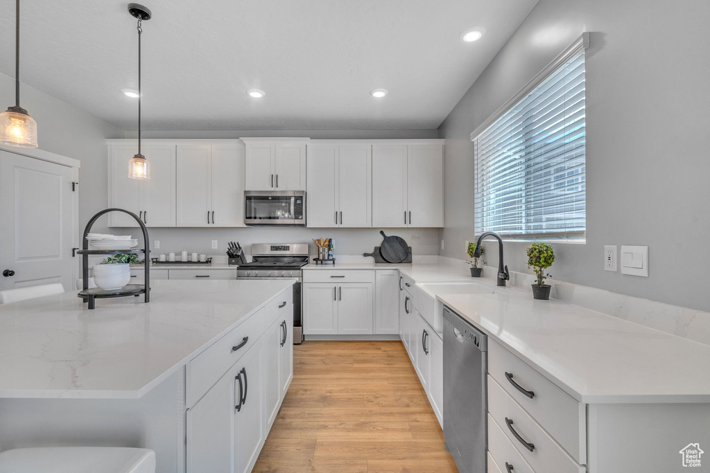 Kitchen featuring stainless steel appliances, a sink, recessed lighting, white cabinets, and pendant lighting