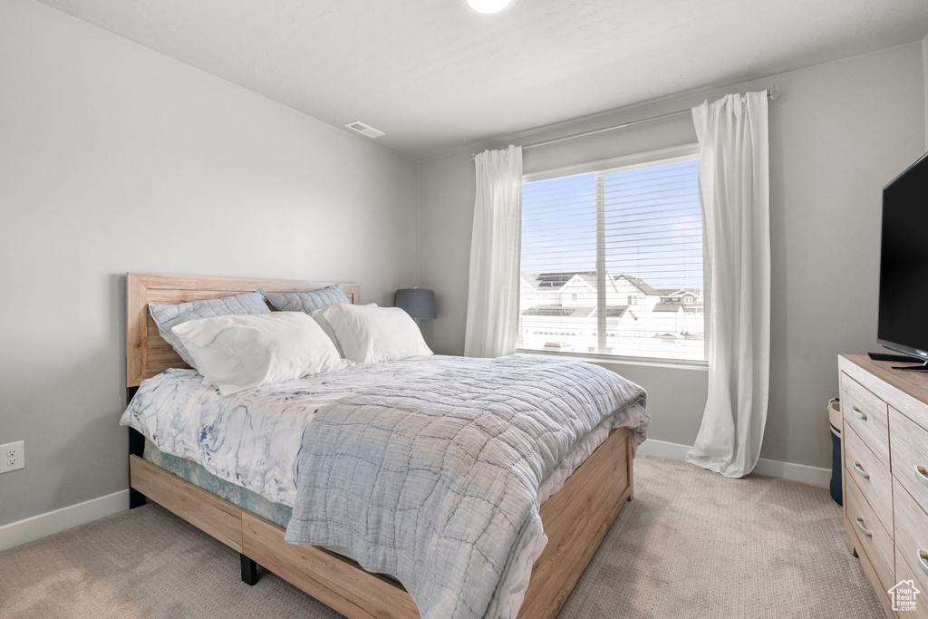Bedroom with light colored carpet and baseboards