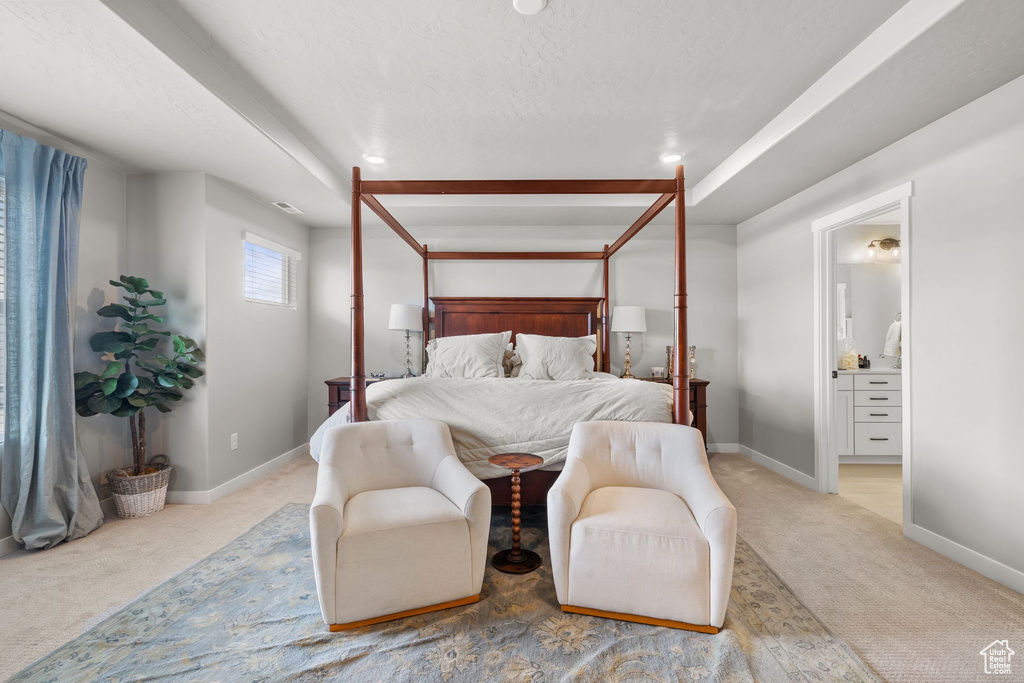 Bedroom with light carpet, ensuite bath, baseboards, and a textured ceiling