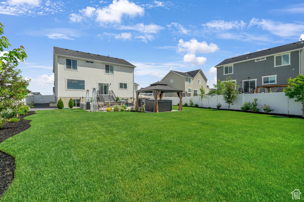 Rear view of property featuring a gazebo, stucco siding, and a residential view