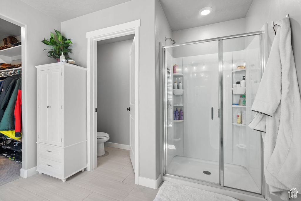 Full bath with a shower stall, toilet, baseboards, and a walk in closet