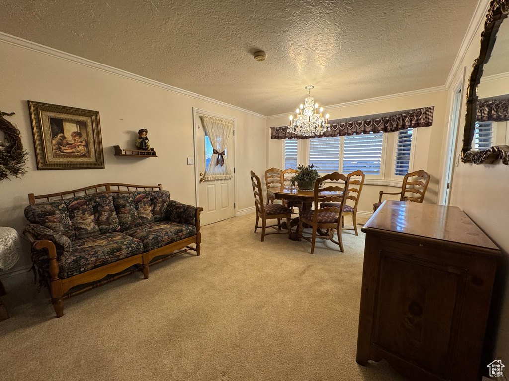 Dining area featuring ornamental molding, a chandelier, light colored carpet, a textured ceiling, and baseboards