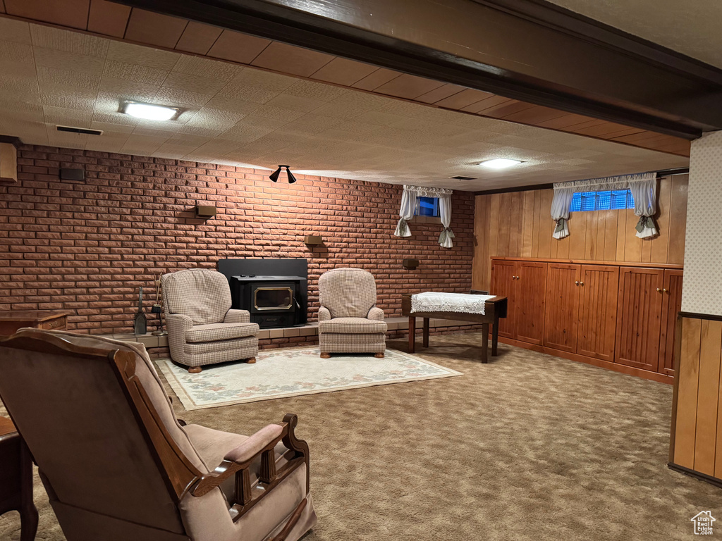 Carpeted living area featuring a wood stove, brick wall, and wood walls