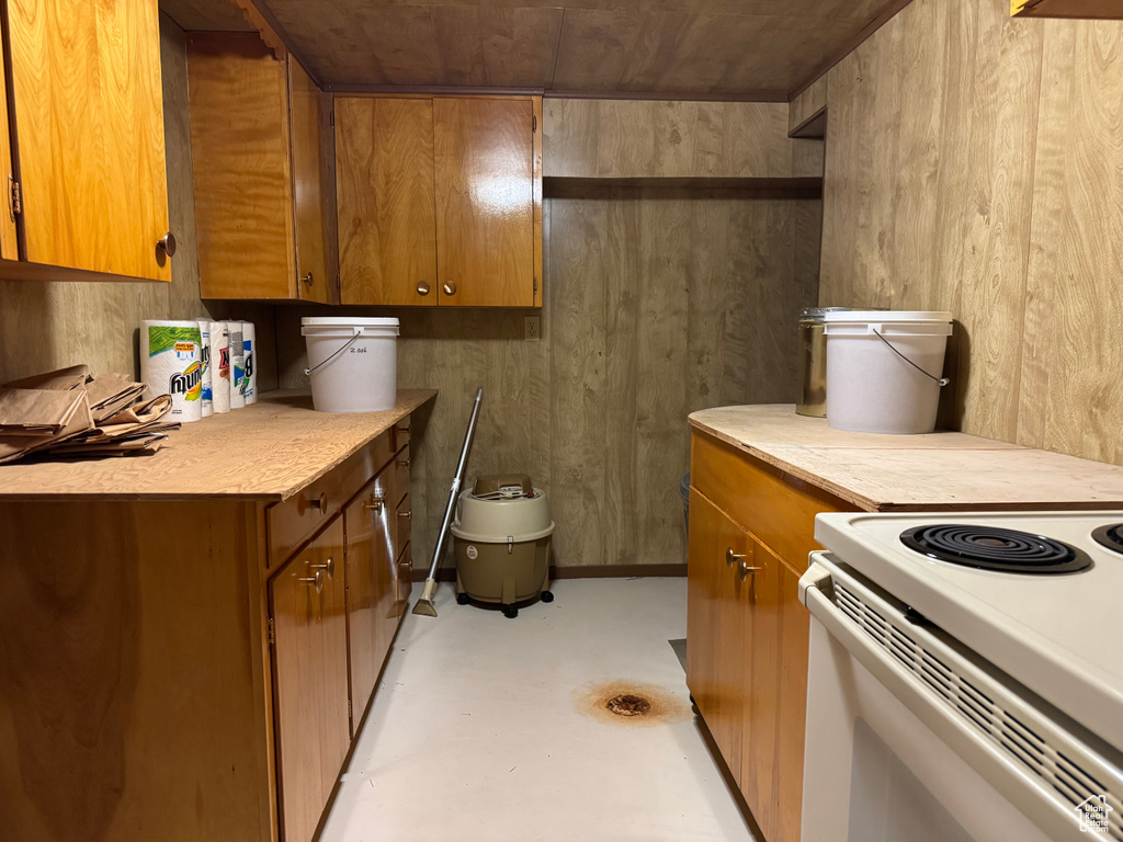 Kitchen with brown cabinetry, light countertops, finished concrete floors, and white electric range