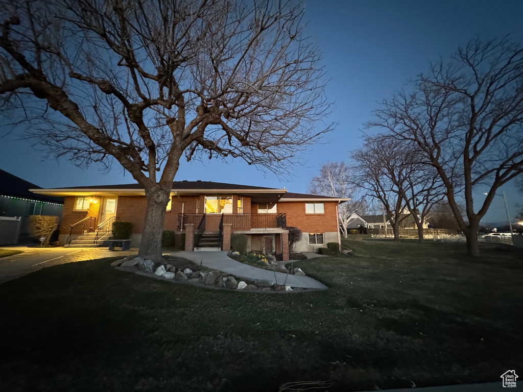 Rear view of property featuring brick siding, a lawn, and stairway