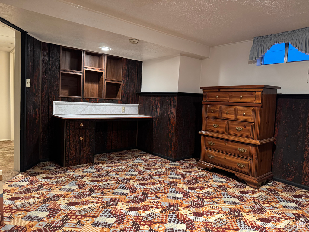 Office area with a wainscoted wall, a textured ceiling, and wood walls
