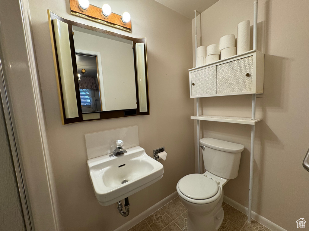 Bathroom featuring a sink, toilet, baseboards, and tile patterned flooring