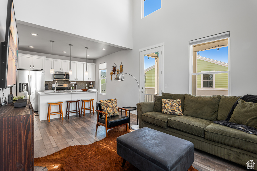 Living room featuring dark wood finished floors, plenty of natural light, recessed lighting, and a towering ceiling