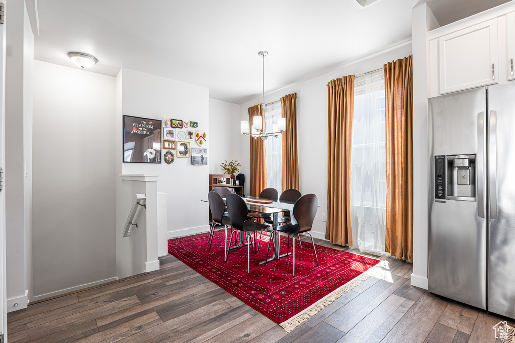 Dining space featuring dark wood-style flooring, a chandelier, and baseboards