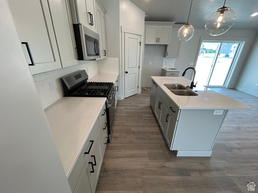 Kitchen with stainless steel microwave, range with gas stovetop, a sink, and dark wood-style floors