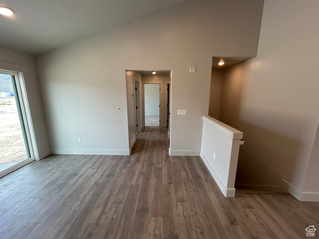 Empty room featuring wood finished floors, baseboards, and lofted ceiling