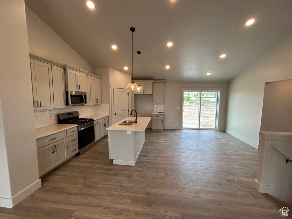 Kitchen featuring appliances with stainless steel finishes, a sink, decorative backsplash, recessed lighting, and lofted ceiling