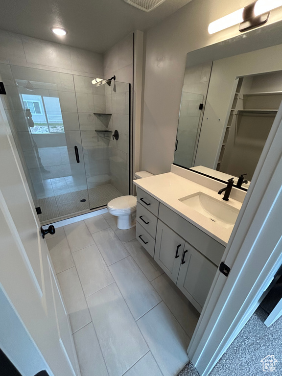 Full bathroom featuring vanity, a shower stall, a spacious closet, and toilet