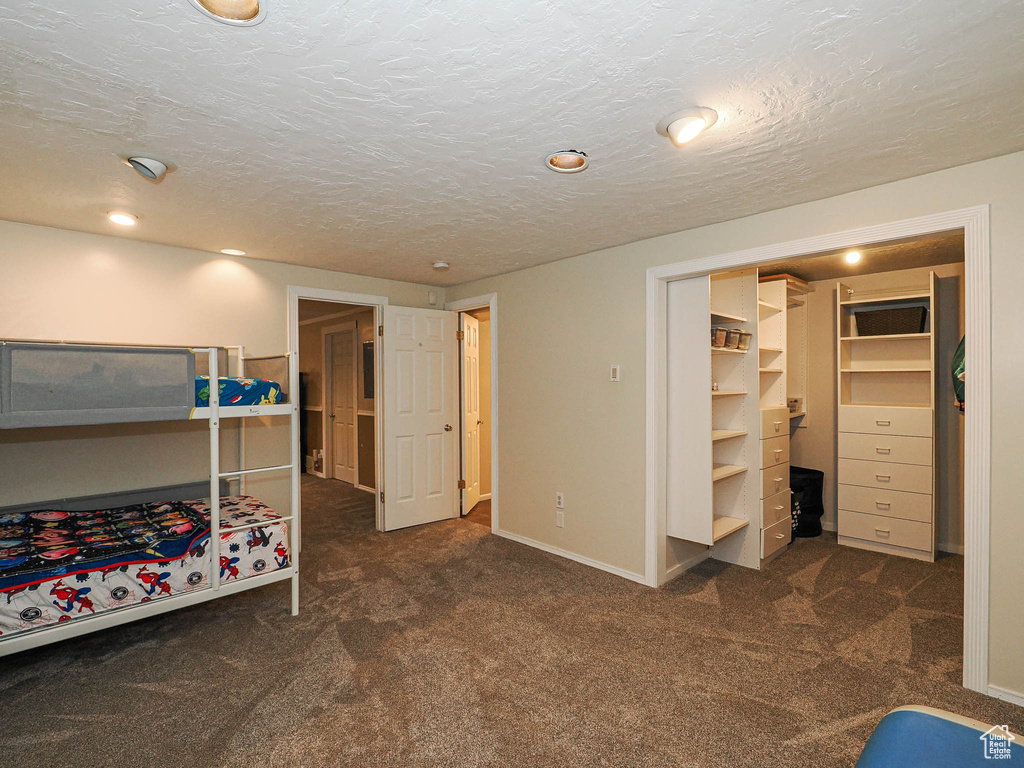 Bedroom featuring carpet floors, a textured ceiling, and a walk in closet