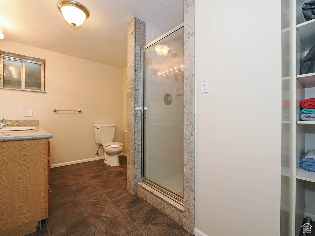 Full bath with vanity, a shower stall, toilet, and baseboards