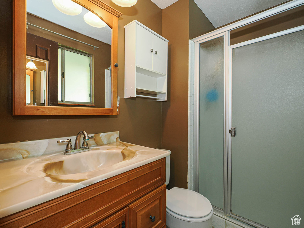 Full bathroom featuring vanity, a shower stall, and toilet