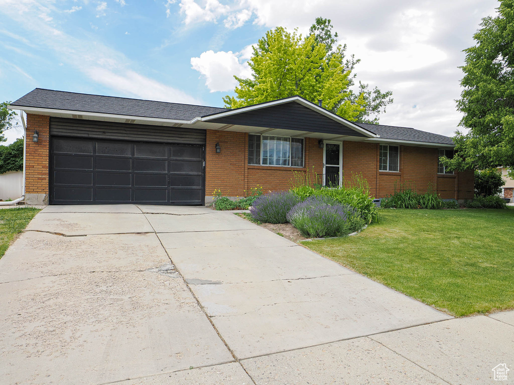 Ranch-style house with an attached garage, brick siding, a front yard, and concrete driveway