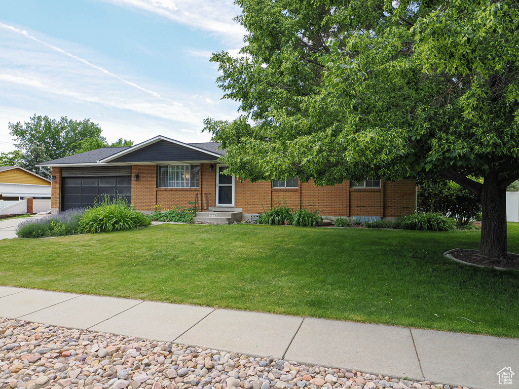 Single story home with brick siding, a garage, and a front yard