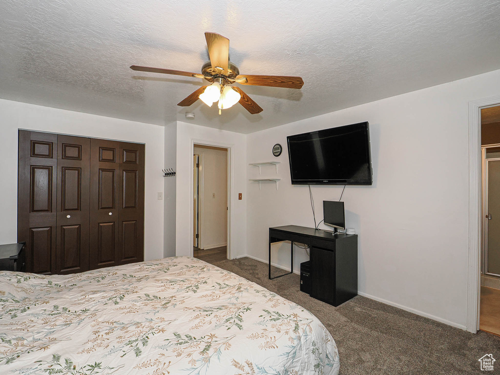 Carpeted bedroom with a textured ceiling, a closet, baseboards, and ceiling fan